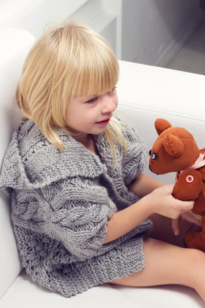Dziewczynka z niedźwiedzia na kanapie — Zdjęcie stockowe