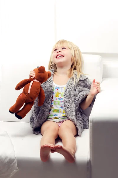 Little girl with bear on sofa — Stock Photo, Image