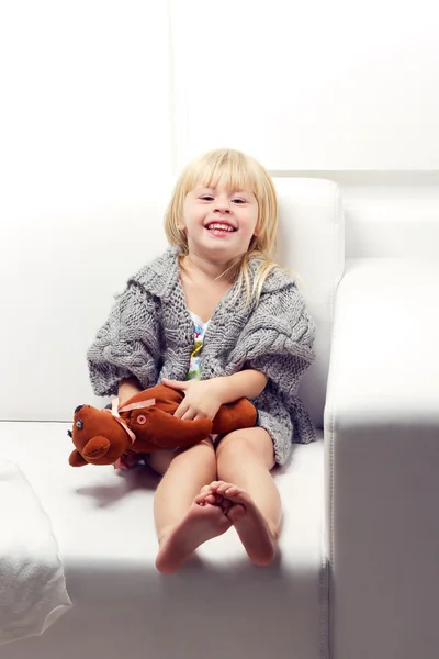 Little girl with bear on sofa — Stock Photo, Image