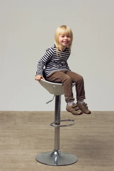 Niña 3 años de edad en jeans se sienta en una silla alta —  Fotos de Stock