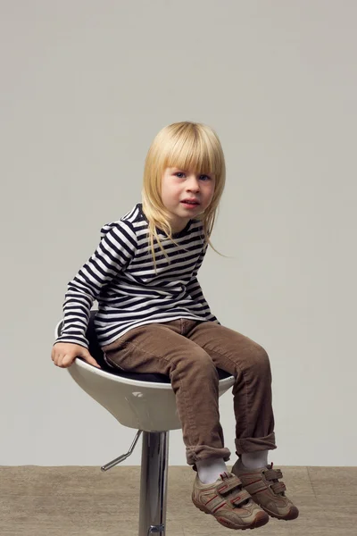 Niña 3 años de edad en jeans se sienta en una silla alta —  Fotos de Stock