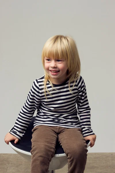 Meisje 3 jaar oud in spijkerbroek zit op een hoge stoel — Stockfoto