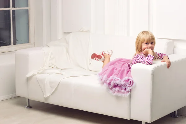 Liten flicka poserar glatt på soffa — Stockfoto