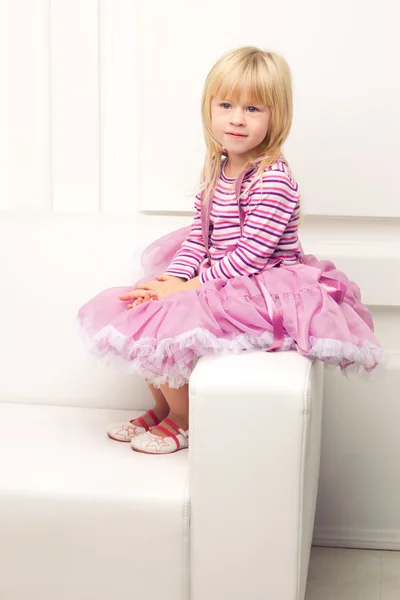 Malá holčička šťastně pózuje na pohovce — Stock fotografie