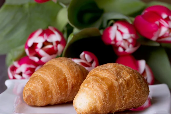 Zwei Croissants neben einem Strauß Tulpen — Stockfoto