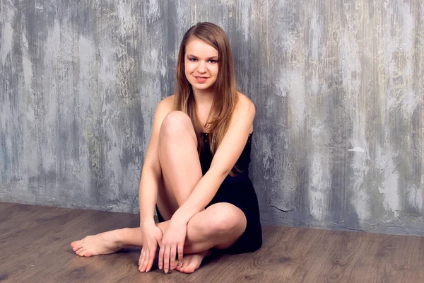 Beatiful girl sitting near wall — Stock Photo, Image