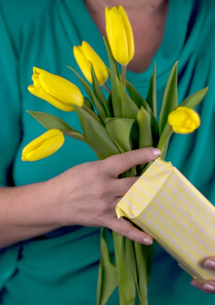 Hands of an adult woman with yellow tulips — Stock Photo, Image