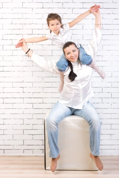 Girl in jeans sitting on the neck of his mother — Stock Photo, Image