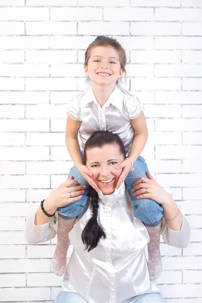 Mädchen sitzt auf dem Hals seiner Mutter — Stockfoto
