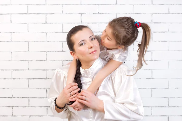 Hija en un vestido blanco besando a su madre — Foto de Stock