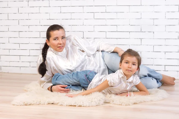 Mother and daughter lying on fur rug at home — Stock Photo, Image