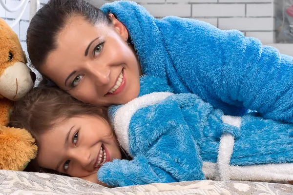 Happy mother and daughter in blue terry robes — Stock Photo, Image