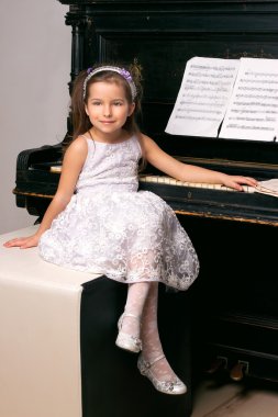 girl in a black dress sitting near the piano