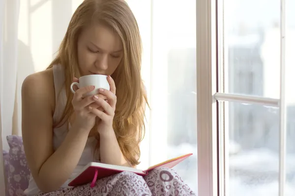 Az ablak tea fogyasztása mellett lány — Stock Fotó