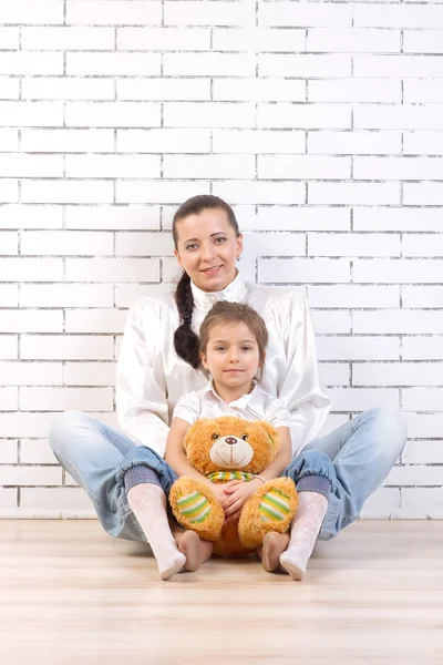 Mãe e filha sentadas, segurando um brinquedo — Fotografia de Stock