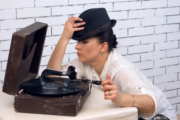 Donna in un cappello a metà turno vicino al grammofono — Foto Stock