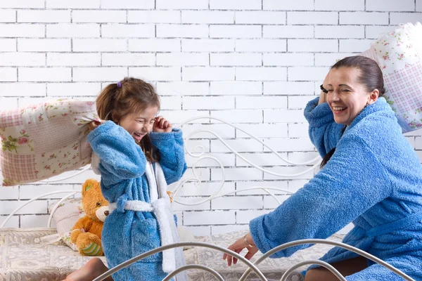 Mutter und Tochter in Frottee-Roben schlagen Kissen — Stockfoto