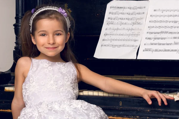 Mädchen in schönem Kleid sitzt am Klavier — Stockfoto