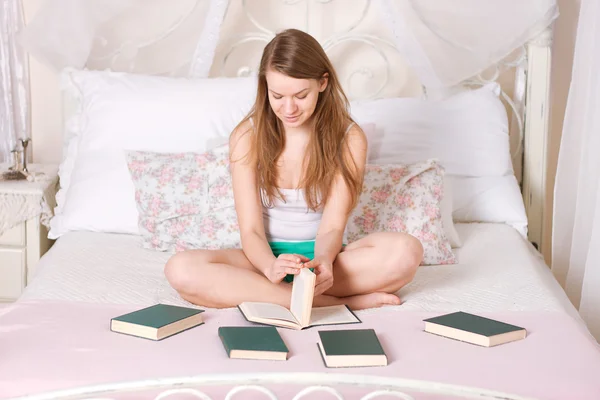 Genç kadın yatakta kitap okuyor. — Stok fotoğraf