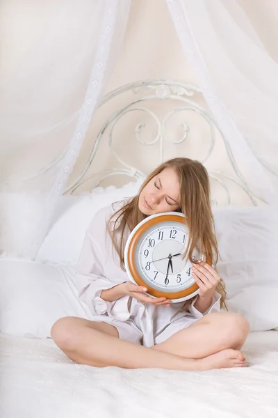 Jonge mooie vrouw in bed en wekker — Stockfoto