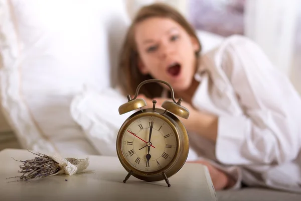 Reloj despertador en mesa y mujer durmiendo —  Fotos de Stock