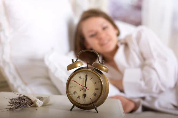 Relógio de alarme na mesa e mulher dormindo — Fotografia de Stock