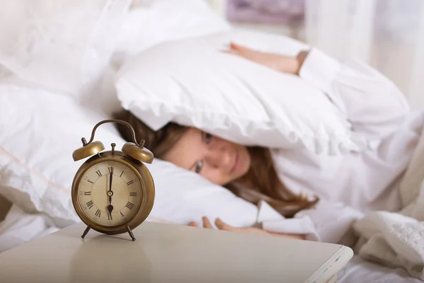 Reloj despertador en mesa y mujer durmiendo — Foto de Stock