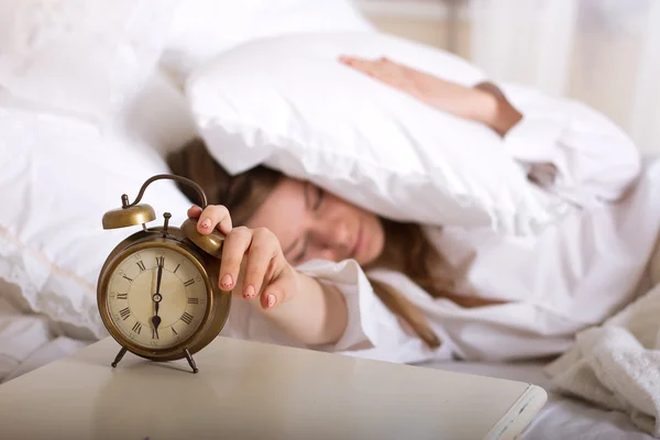 Reloj despertador en mesa y mujer durmiendo — Foto de Stock