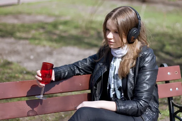 Chica en un banco del parque bebiendo — Foto de Stock