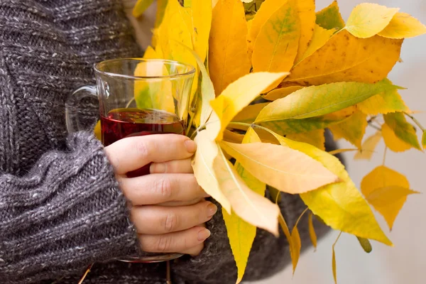 Mano femminile che tiene il tè e foglie d'autunno — Foto Stock
