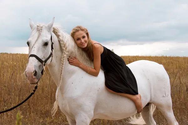 Menina no vestido preto está montando no cavalo — Fotografia de Stock