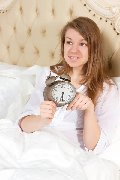 Mujer joven con despertador en la cama —  Fotos de Stock