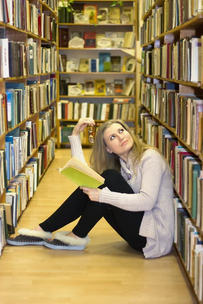 Девушка сидит на полу в старой библиотеке — стоковое фото