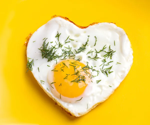 Fried eggs in a heart shape with dill — Stock Photo, Image