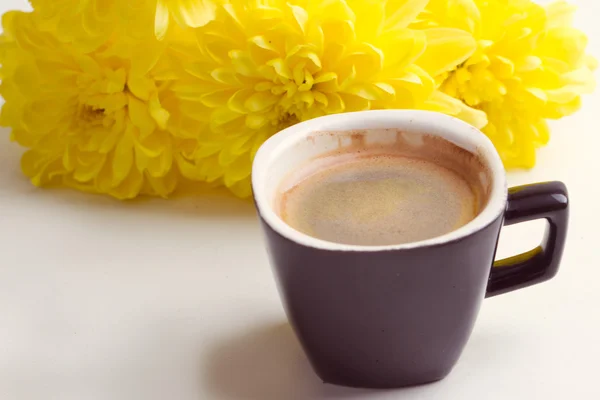 Schwarzer Kaffee in der Nähe der gelben Blumen — Stockfoto