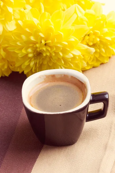 Czarna kawa w pobliżu żółte kwiaty — Zdjęcie stockowe