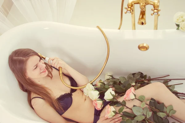 Mädchen liegt mit Rosen im Badezimmer — Stockfoto