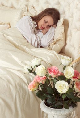 Gül ile yatakta uyuyan güzel kadın
