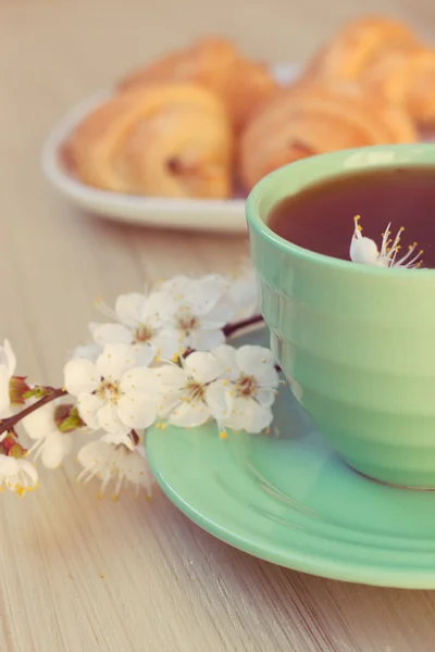 Fincan çay ve kruvasan yakınındaki çiçek şube — Stok fotoğraf