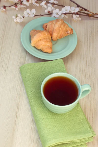 Cup of tea and croissants near blossoming branches — Stock Photo, Image