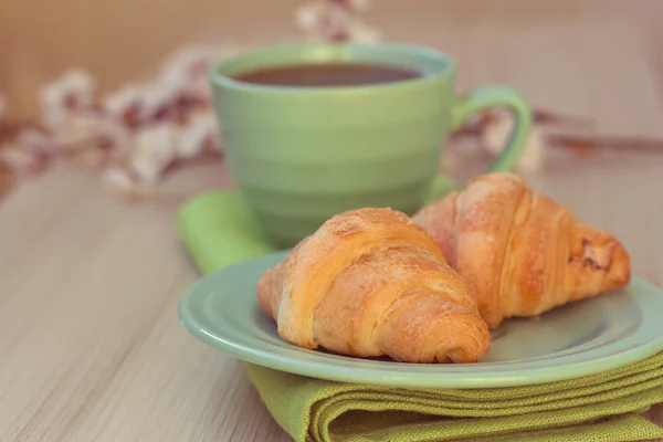 Cup of tea and croissants near blossoming branches — Stock Photo, Image