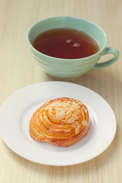 Bun and cup of tea on tray — Stock Photo, Image