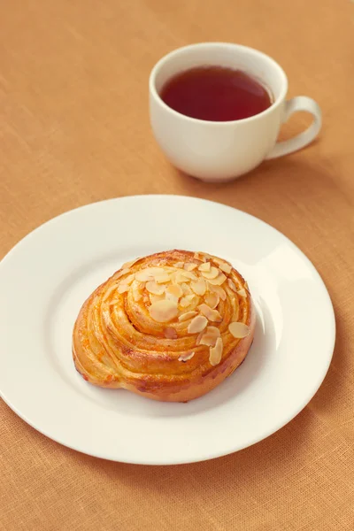 Bun and cup of tea on tray — Stock Photo, Image