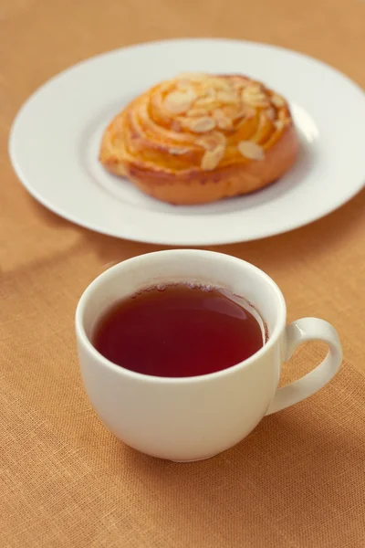 Булочка и чашка чая на подносе — стоковое фото