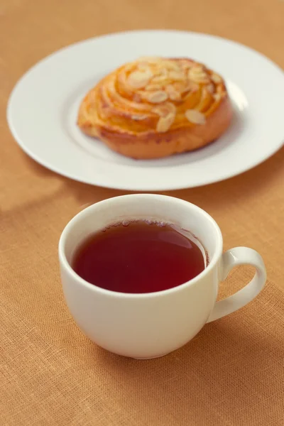 Bun and cup of tea on tray — Stock Photo, Image