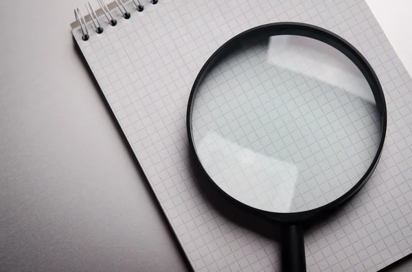 Magnifying glass and notebook — Stock Photo, Image