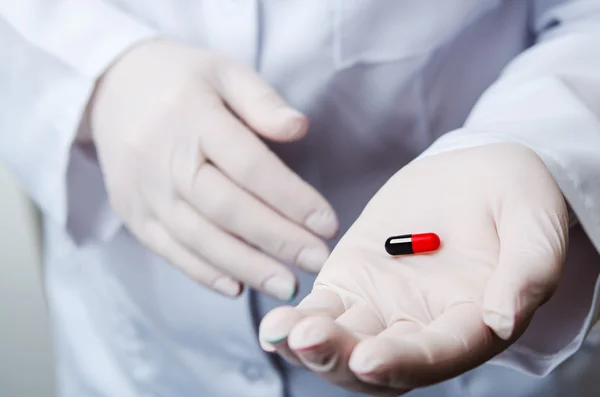 Doctor holding red capsule — Stock Photo, Image