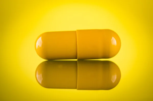 One yellow pill capsule — Stock Photo, Image