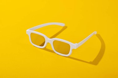 Sarı arka planda beyaz 3D film gözlükleri.