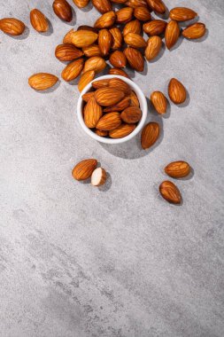 Gri taş arka planda beyaz bir kasede tatlı bademler. en üstteki görünüm